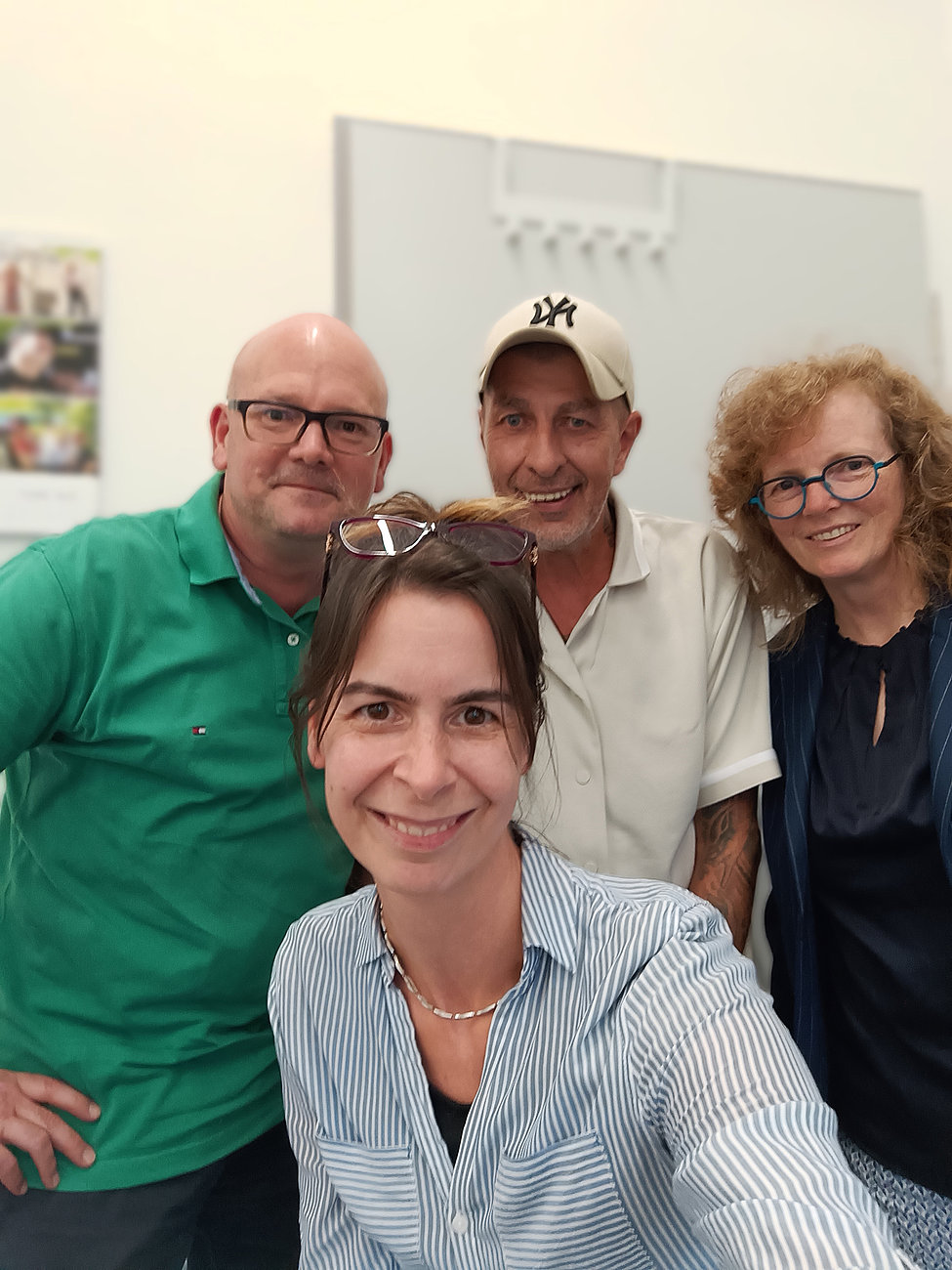 Zwei Frauen und zwei Männer stehen für ein Selfie zusammen und lächeln in die Kamera.