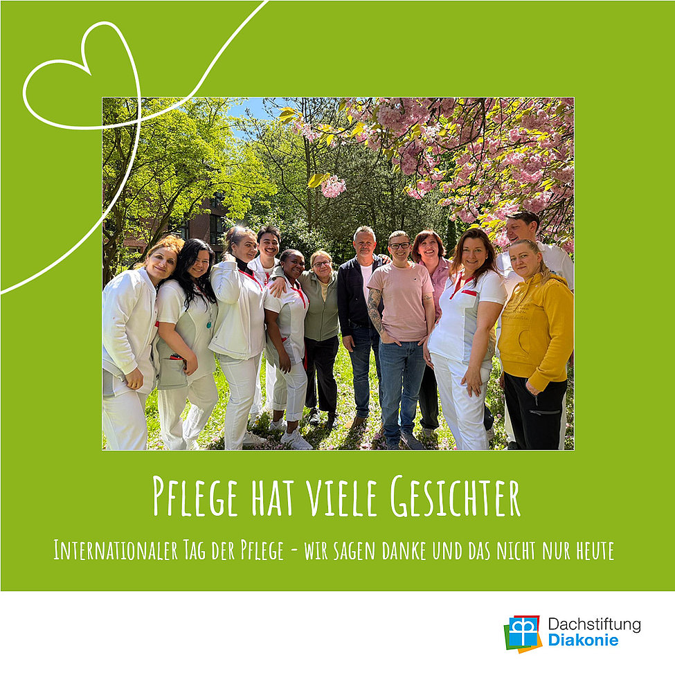 Gruppe von Pflegekräften und Mitarbeitenden lächelnd unter blühenden Bäumen auf grünem Poster mit Schriftzug „Pflege hat viele Gesichter“.