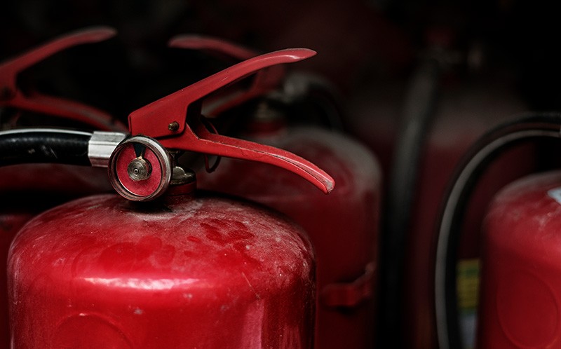 Eine Reihe von Feuerlöschern, von denen der obere Teil im Bildausschnitt zu sehen ist.
